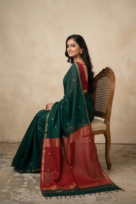 Woman wearing a green and red saree with a plain background