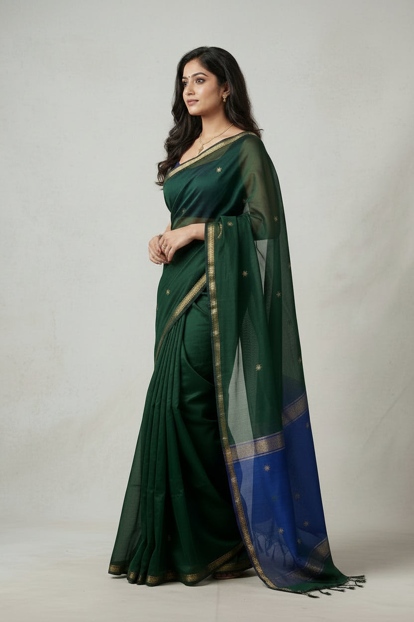 Woman wearing a green saree with a blue border on a plain background