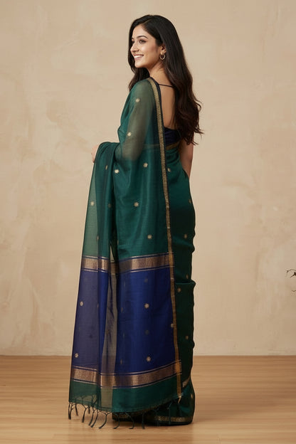 Woman wearing a green and blue saree with a beige background