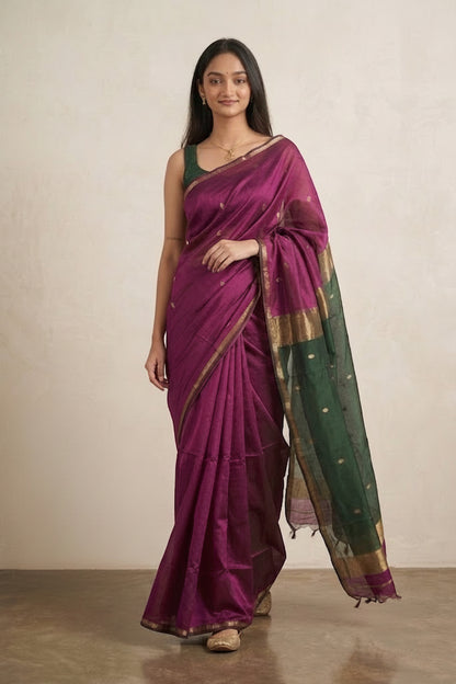 Woman wearing a purple and green saree with a plant in the background