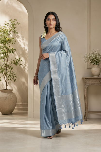 Woman wearing a light blue saree with a white border in an indoor setting.